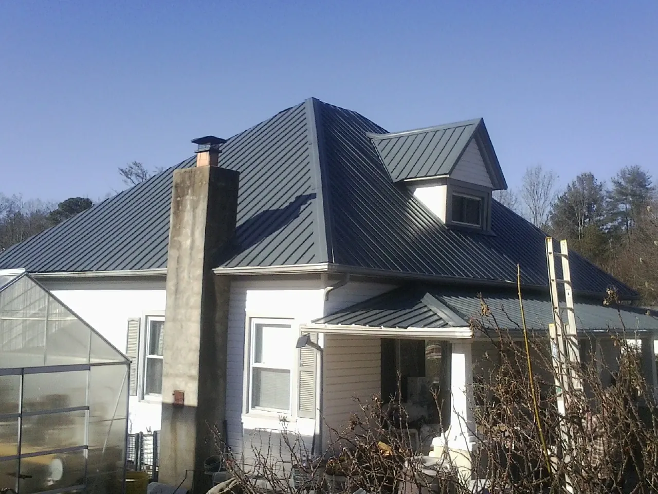 Dark blue standing seam metal roof on a white farmhouse with dormer — Slate & Tile Roof Repair by Roofing Brothers in Kenvil