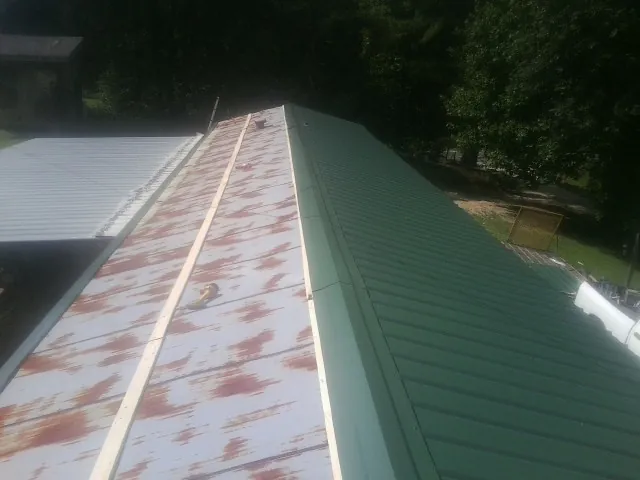 Old rusted panels beside newly installed green metal roofing — Wind Damage Roof Repair by Roofing Brothers in Kenvil