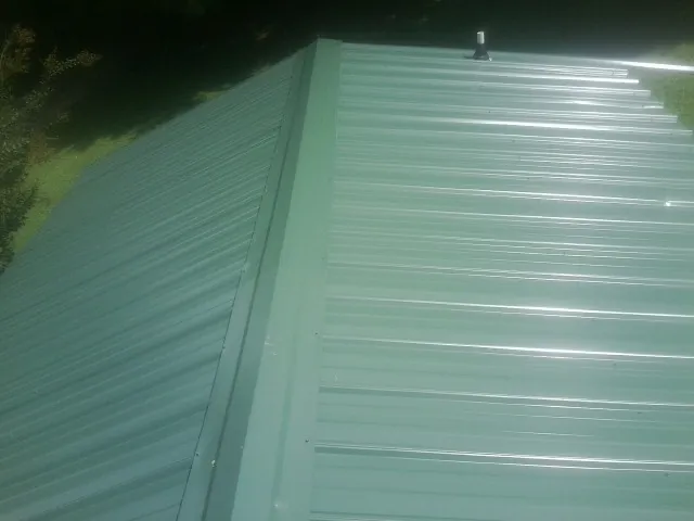 New green metal panels meeting at the ridge of a roof — Flat Roof Repair work by our crew in Kenvil