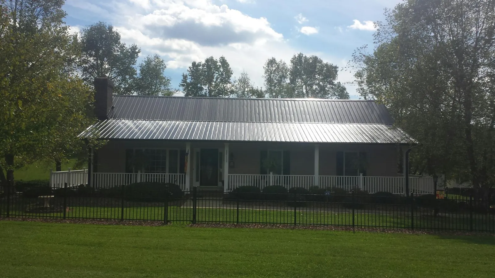 Gray metal roof on a brick ranch with a full width front porch — Gutter Guard Installation work by our crew in Kenvil