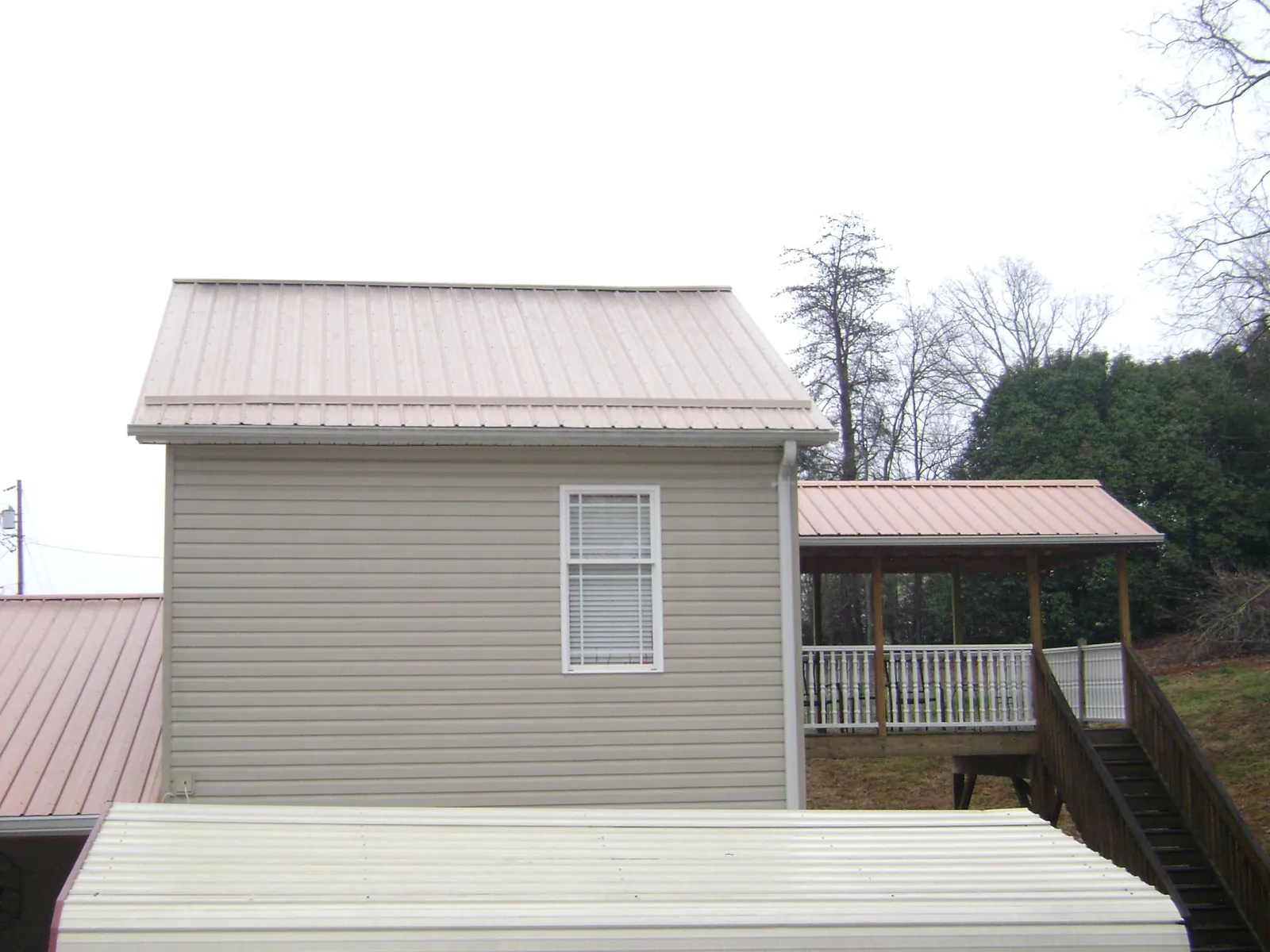 Tan metal roofs on a two story addition and attached porch, from a Roof Replacement job in Kenvil